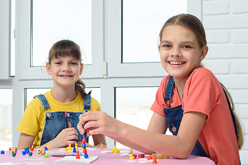 Image showing Two happy girls play a board game and looked at the frame