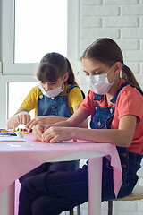 Image showing Two sisters in medical masks play board games