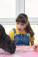 Image showing The girl was very surprised when a cat jumped onto the table with a board game