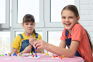 Image showing One girl laughs cheerfully, the other makes faces, children play a board game