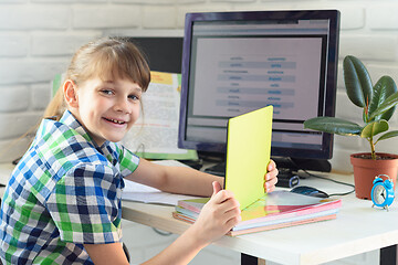 Image showing Girl enjoys doing homework at the computer