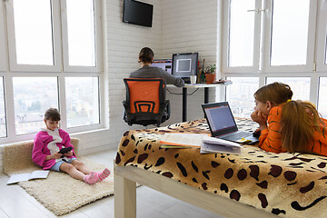 Image showing two children and an adult work in different electronic devices at home