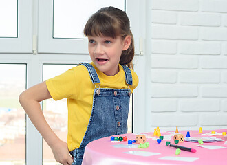Image showing Cheerful girl with a funny face sits at a table playing a board game