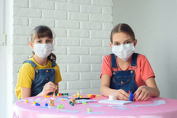 Image showing Two girls in protective medical masks play board games at home