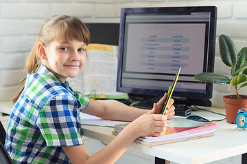 Image showing student at home at a computer table with a tablet in his hands