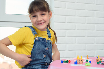 Image showing A contented nine-year-old girl looked into the frame, sitting at the table and playing a board game