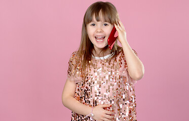 Image showing Cheerful little blonde kid girl 6-7 years old in sequin dress talking on mobile phone.