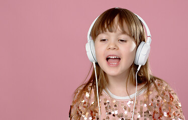 Image showing Pretty 6 or 7 years old little girl singing and dancing with headphones