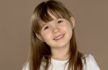 Image showing Portrait of a little cute 7 year old girl in a white tshirt, posing and smiling