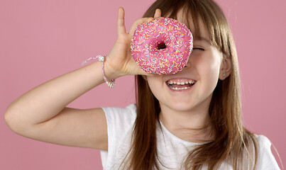 Image showing Young beautiful happy and excited blond girl 6 or 7 years old holding donut on her eyes
