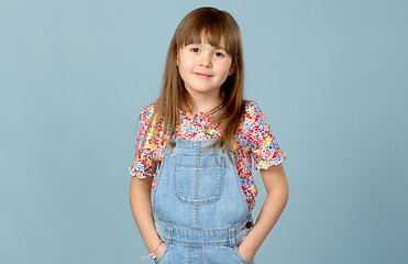 Image showing Cute little girl standing in dungarees jeans with hands in pockets