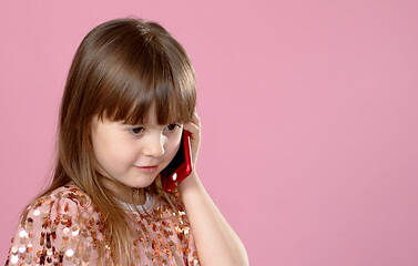 Image showing Cheerful little blonde kid girl 6-7 years old in sequin dress talking on mobile phone.