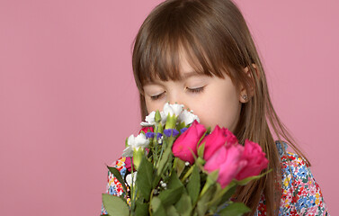 Image showing Cute young adorable girl holding and smell bouquet of fresh flowers