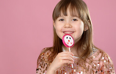 Image showing Young happy, smiled, pretty little girl with sweet lollypop candy. Standing in sequined dress