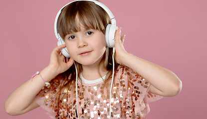 Image showing Cute little girl posing and dancing with headphones while listen to the music