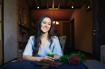 Image showing Smiling vegetarian woman sitting at the table with celery fresh 