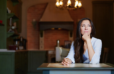 Image showing Serious staying at home woman sitting at the table