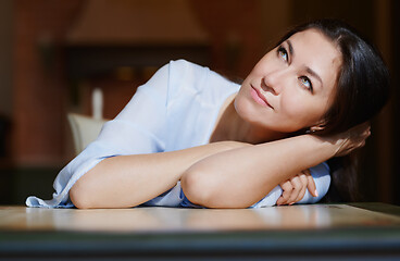 Image showing Serious staying at home woman laying on the table