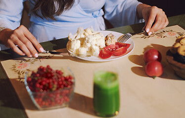 Image showing Vegetarian woman sitting at the table and eating healthy food