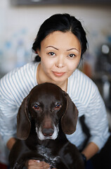 Image showing Woman at home hugging her dog