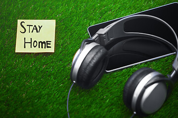 Image showing Stay Home text on sticky note on a grass with headphones and dig