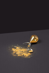 Image showing Broken antique sandglass with golden sand on a black duotone background.