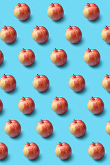 Image showing Creative pattern from fresh organic red apples on a blue background.