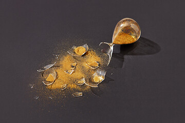 Image showing Crashed sandglass with golden sand on a black background.