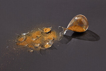 Image showing Broken antique hourglass with golden sand on a black background.