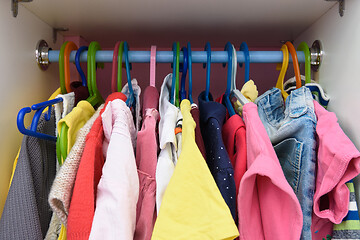 Image showing Baby things are hanging in the closet on hangers