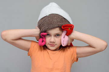 Image showing The girl put on a lot of things on her head so as not to hear loud sounds