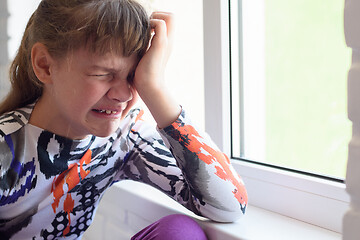 Image showing Teen girl crying a lot while sitting by the window in the room, close-up