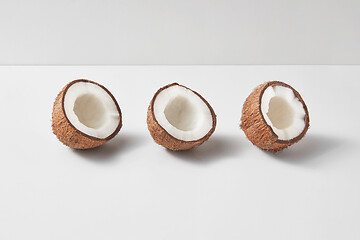 Image showing Set from three tropical natural halves of coconut on a light grey background.