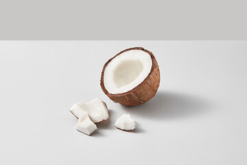 Image showing Fresh half of ripe organic tropical coconut fruit on a light grey background.