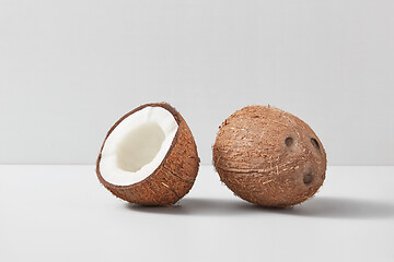 Image showing Half and whole natural organic coconut fruits on a duotone grey background.