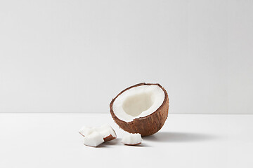 Image showing Half of fresh ripe tropical coconut fruit on a light grey background.