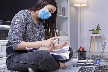 Image showing High school student girl with mask on her face using sanitizer b