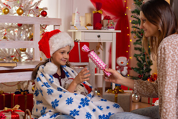 Image showing Girl gives a big candy to a child in the Christmas room