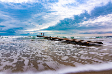 Image showing Sea landscape with beautiful clouds in blue tones, with a pier on the horizon