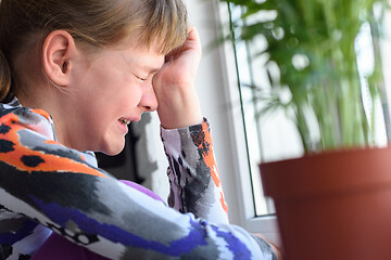 Image showing Ten year old girl sobs at the window in the room