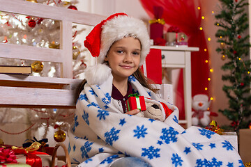 Image showing Girl dressed in A New Year\'s Cap sits covered in plaid