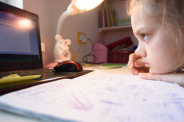 Image showing A very tired girl hates watching video lessons at home