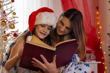 Image showing Girl with child reading a book in a decorated christmas room