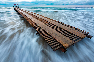 Image showing Wooden pier in a storm covered with a wave, long exposure