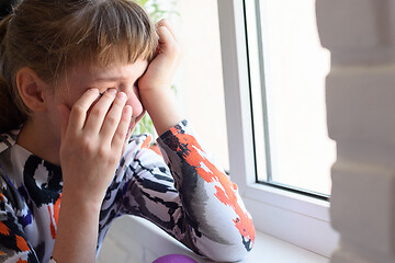 Image showing Offended girl cries bitterly at the window