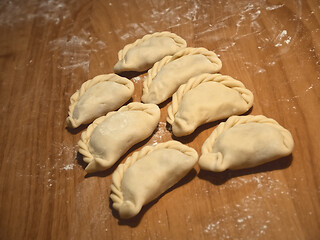 Image showing Six uncooked dumplings on the wooden kitchen board