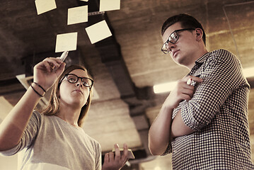 Image showing young couple at modern office interior writing notes on stickers