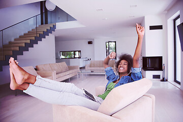 Image showing African american woman at home in chair with tablet and head pho