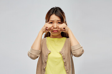 Image showing sad asian woman crying over grey background