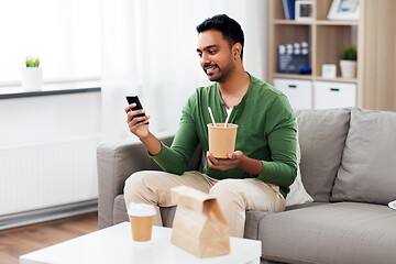 Image showing smiling indian man eating takeaway food at home